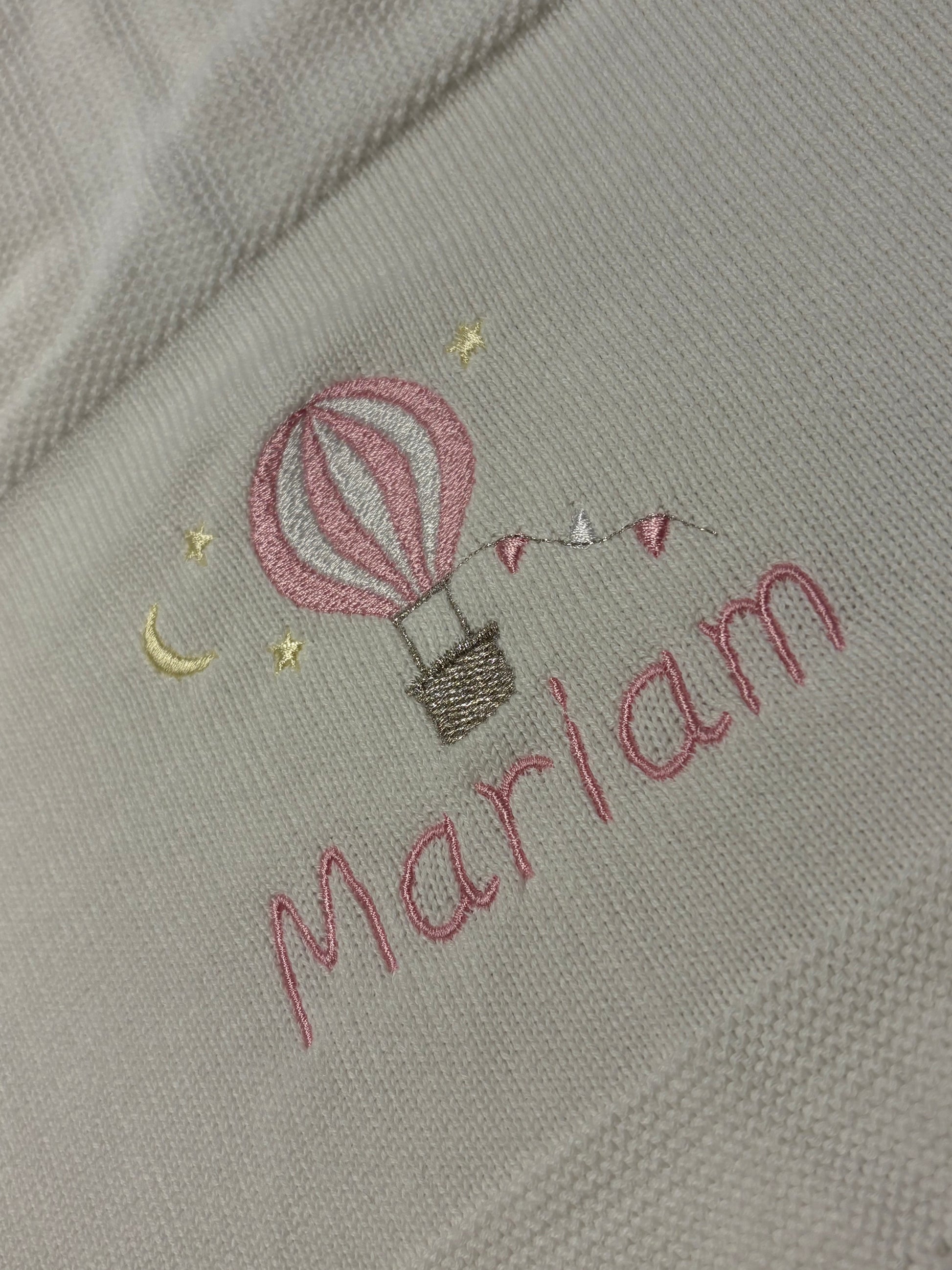 Embroidered motif design on fabric with a hot air balloon and the name 'Mariam' embroidered in pink